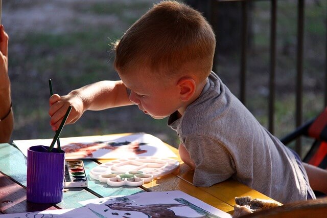 Chłopczyk maluje farbami na dworze