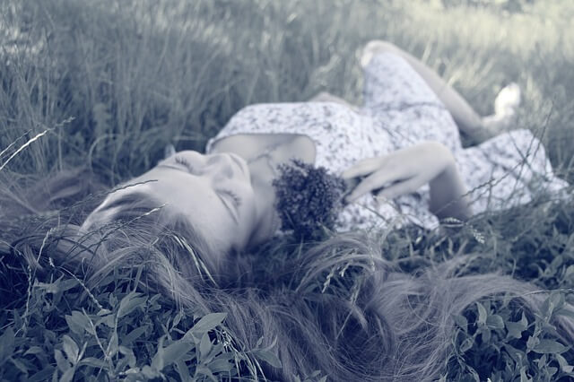 Długowłosa dziewczyna leży w trawie
