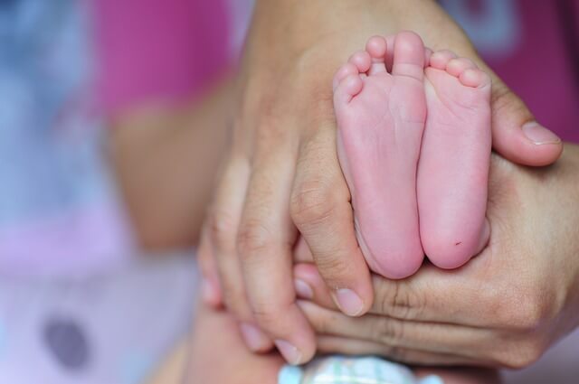 Maleńkie stopy dziecka w dłoniach człowieka
