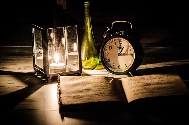 Książka, zegar i świeczka tworzą nastrój tajemnicy