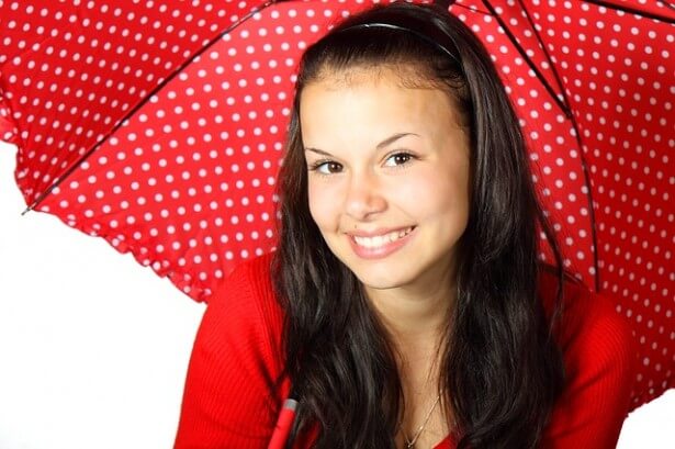 uśmiechnięta dziewczyna pod parasolem