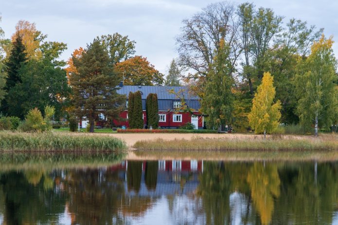 Drewniany dom nad brzegiem jeziora otoczony zielenią drzew